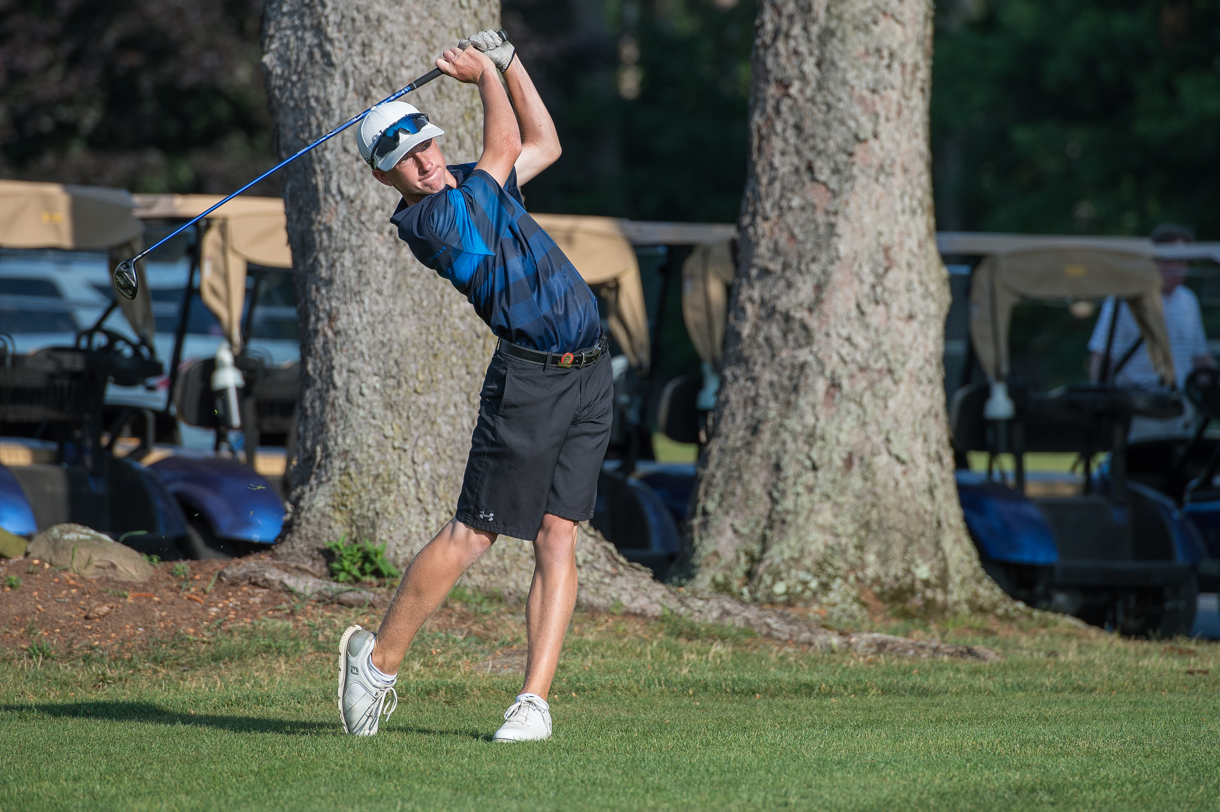 young male golfer with a fairway wood finishing his swing